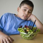 bored little boy looks at person with camera like theyre kidding when they gave him that salad
