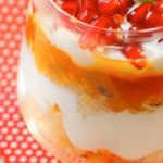 pomegranate orange parfait with spoon laid out on red napkin