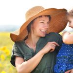 woman tickling little girl in a sunny field full of flowers and fresh air, weight loss and wellness solutions